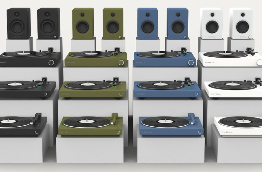 Display of various turntables and speakers in multiple colors including black, green, blue, and white, arranged on a white background.